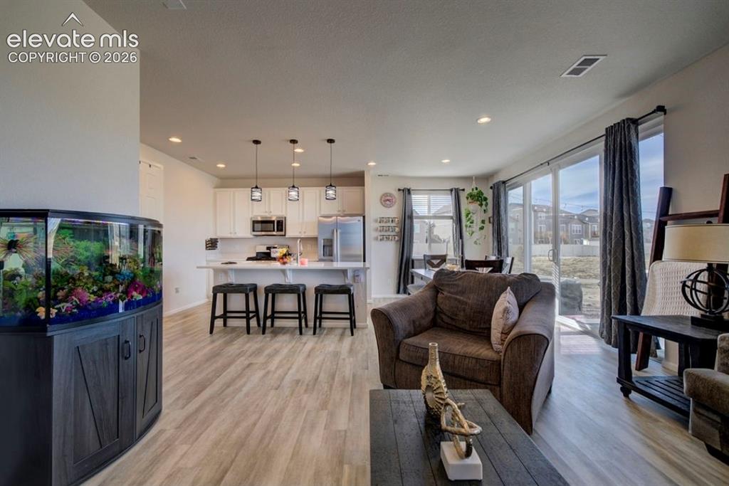 Image 12 of 34: Open-concept living area featuring light wood-finish flooring, recessed lig