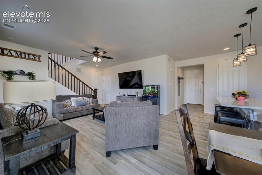 Image 15 of 34: Spacious living area featuring wood-finish flooring, a ceiling fan, and a s