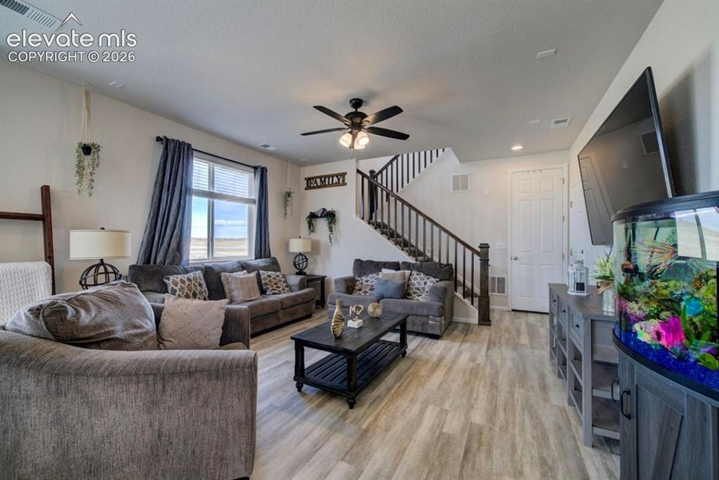 Image 16 of 34: Spacious living area featuring wood-finish flooring, a ceiling fan, and a s