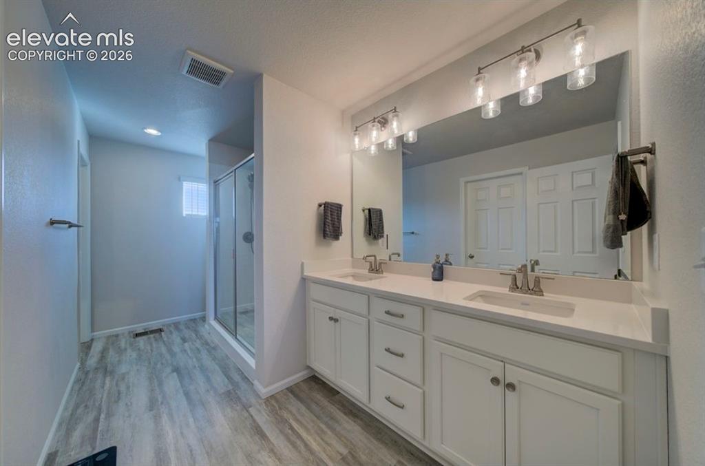 Image 21 of 34: Dual vanity with undermount sinks and light-colored countertops, large wall