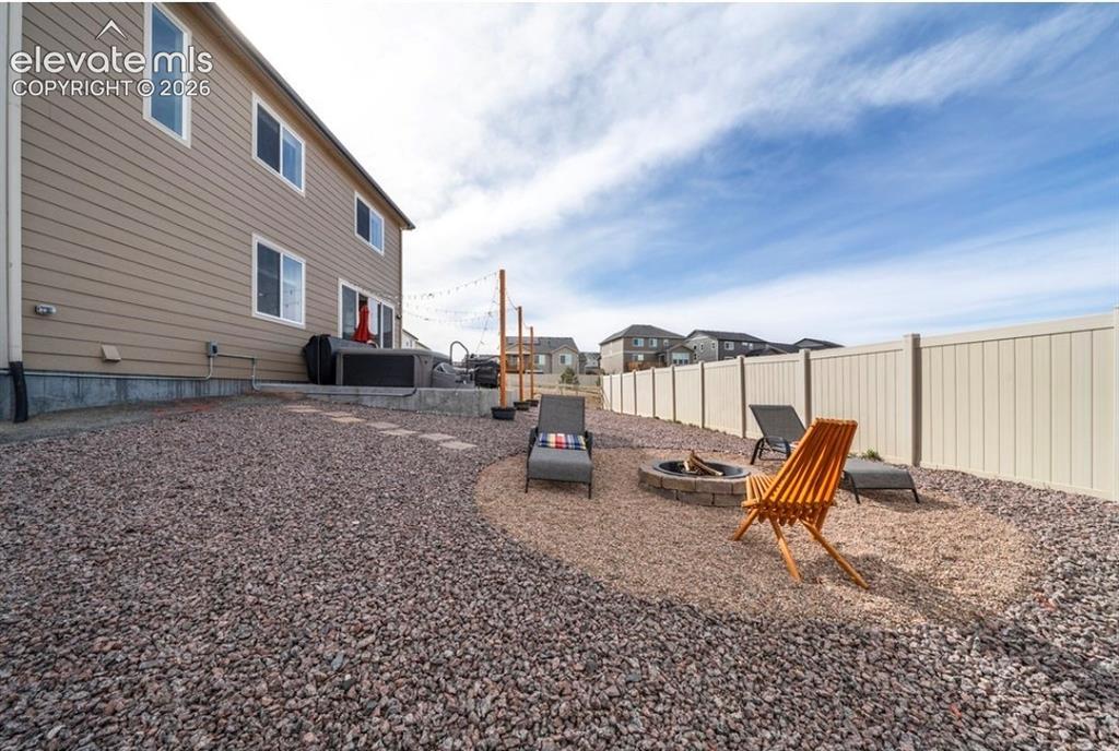 Image 31 of 34: Expansive gravel landscaping with a stone fire pit area, raised concrete pa