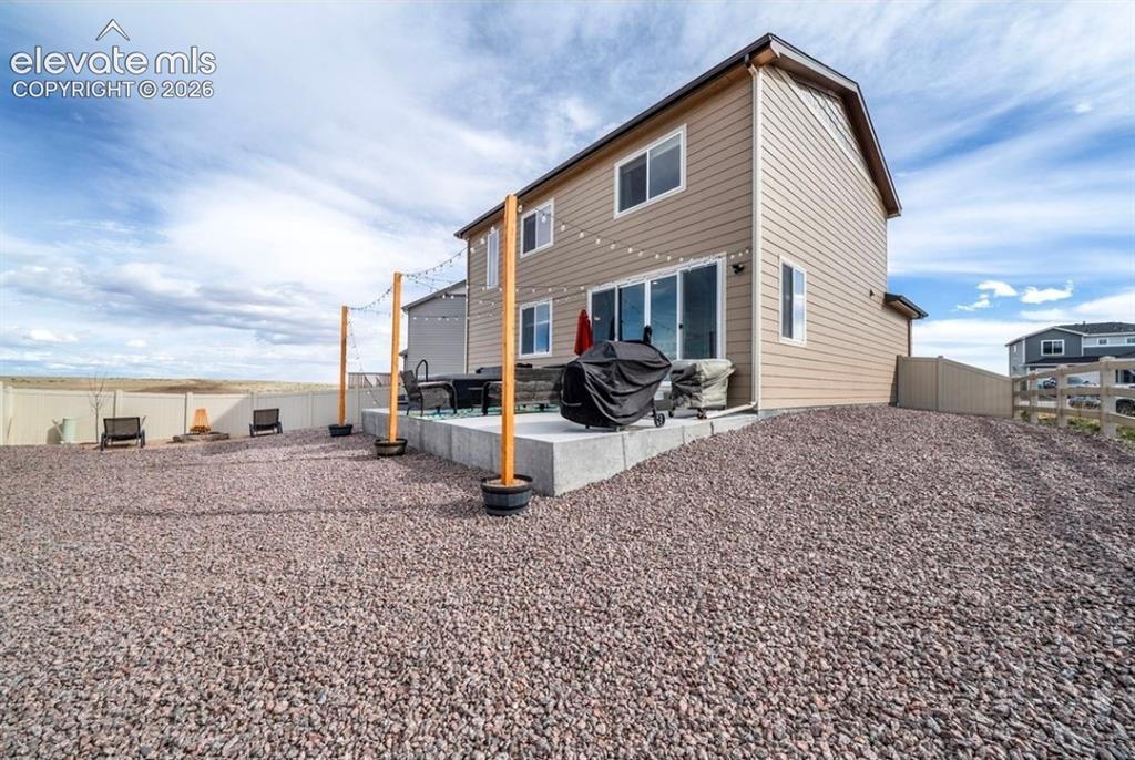 Image 33 of 34: Rear exterior featuring a concrete patio, sliding glass doors, and light-co