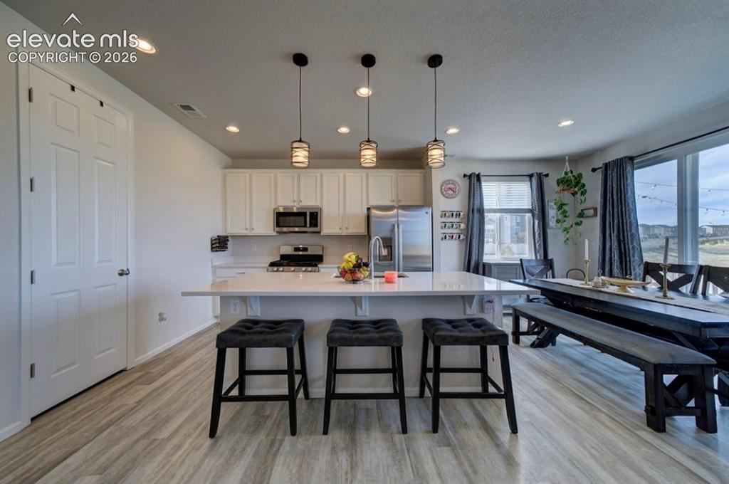 Image 5 of 34: Kitchen featuring white cabinetry, stainless steel appliances, a center isl
