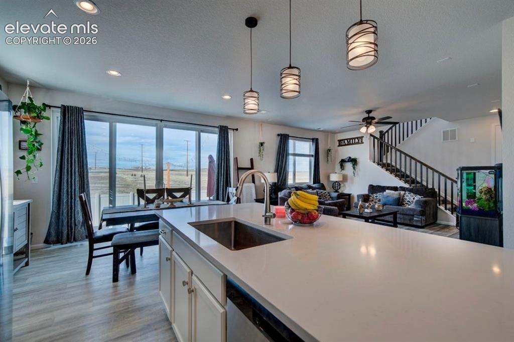 Image 8 of 34: Kitchen island with a built-in sink, pendant lighting, wood-finish flooring