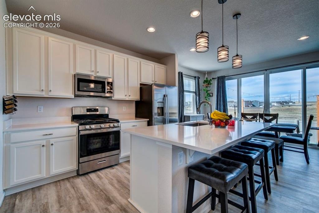 Image 9 of 34: Kitchen featuring white cabinetry, stainless steel appliances, a center isl