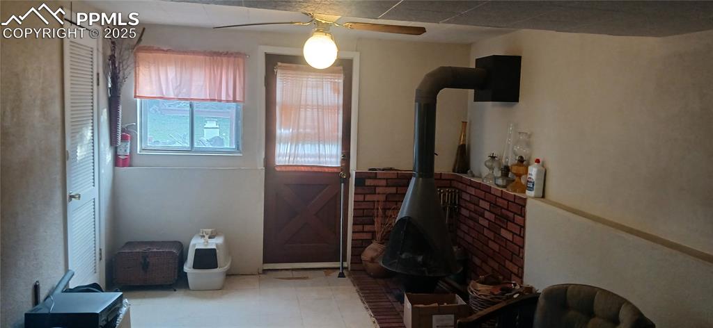 Image 19 of 33: Doorway featuring a wood stove, ceiling fan, and tile patterned floors