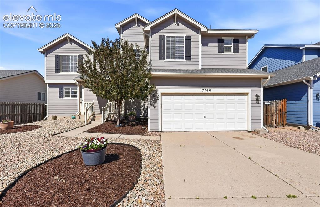 Caption: Two-story residence featuring light gray siding, dark shutters, and a white garage door