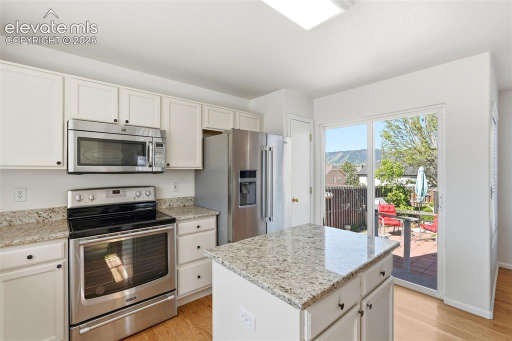 Image 10 of 37: Kitchen featuring white cabinetry, stainless steel appliances, and light-to