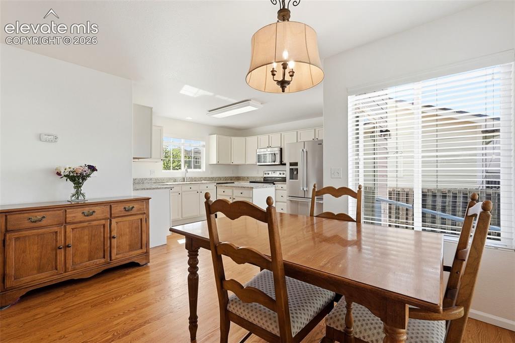 Image 13 of 37: Open-concept dining area with wood-finish flooring, a contemporary chandeli