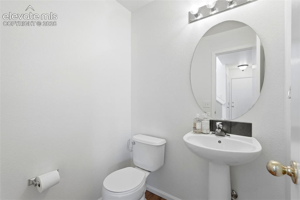 Image 17 of 37: Pedestal sink with chrome faucet, oval mirror, and wall-mounted vanity ligh