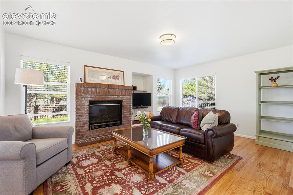 Image 2 of 37: Living area featuring a brick fireplace, built-in shelving, wood-finish flo