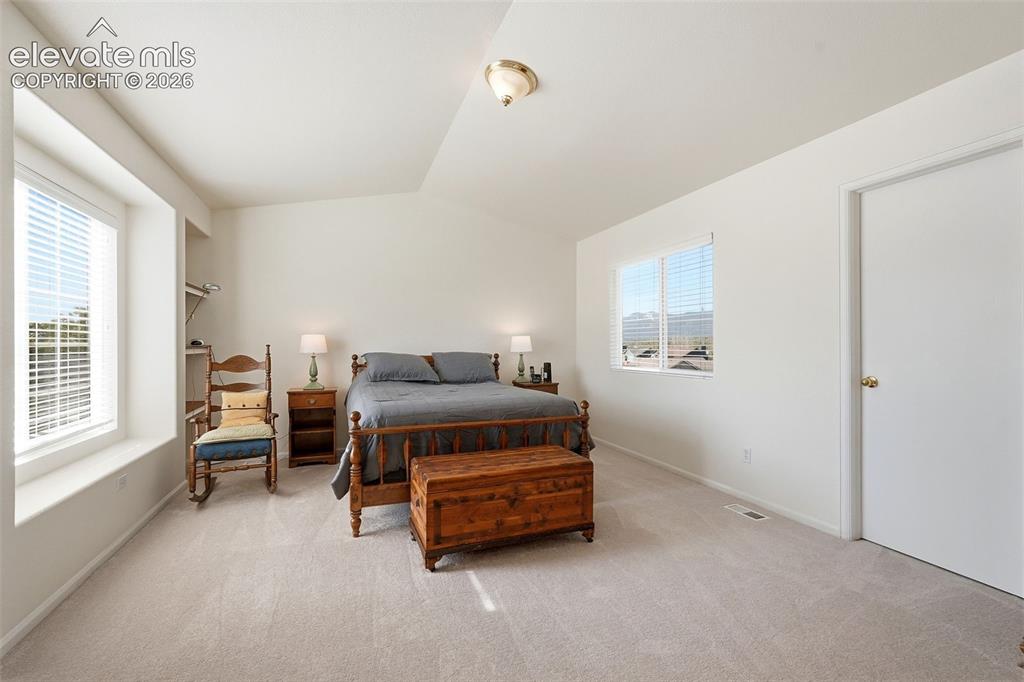 Image 23 of 37: Spacious room featuring neutral carpet flooring, two windows with blinds, a