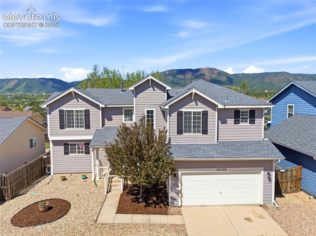 Image 32 of 37: Two-story residence featuring light gray siding, dark shutters, and a promi