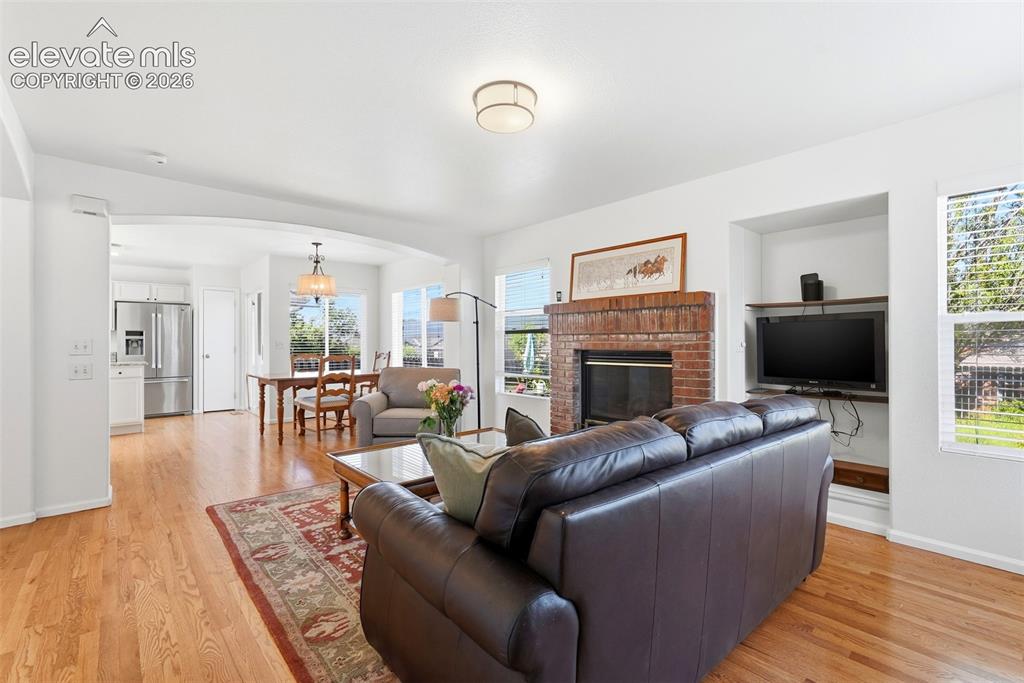 Image 4 of 37: Living space featuring wood-finish flooring, a brick-surround fireplace, an