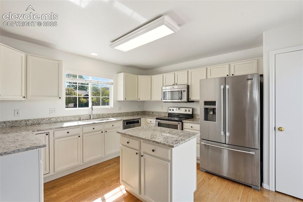 Image 6 of 37: Bright kitchen featuring a central island, white cabinetry, stainless steel