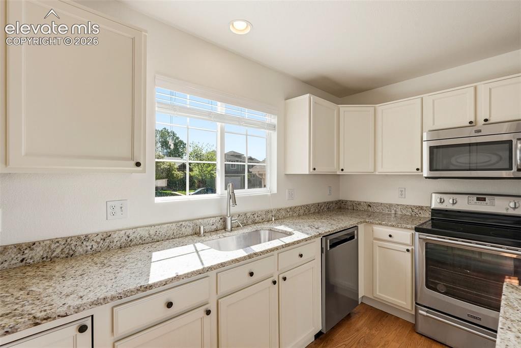 Image 7 of 37: Kitchen featuring light-toned cabinetry, stainless steel appliances, speckl