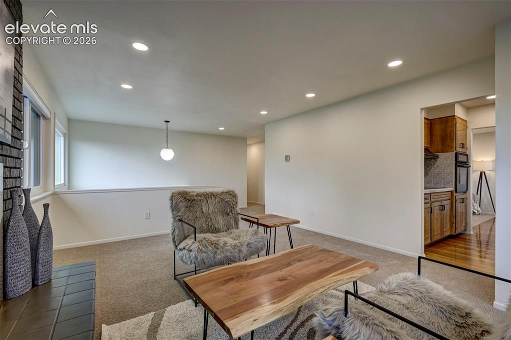 Image 13 of 50: Interior space featuring recessed lighting, a stone-accented fireplace surr