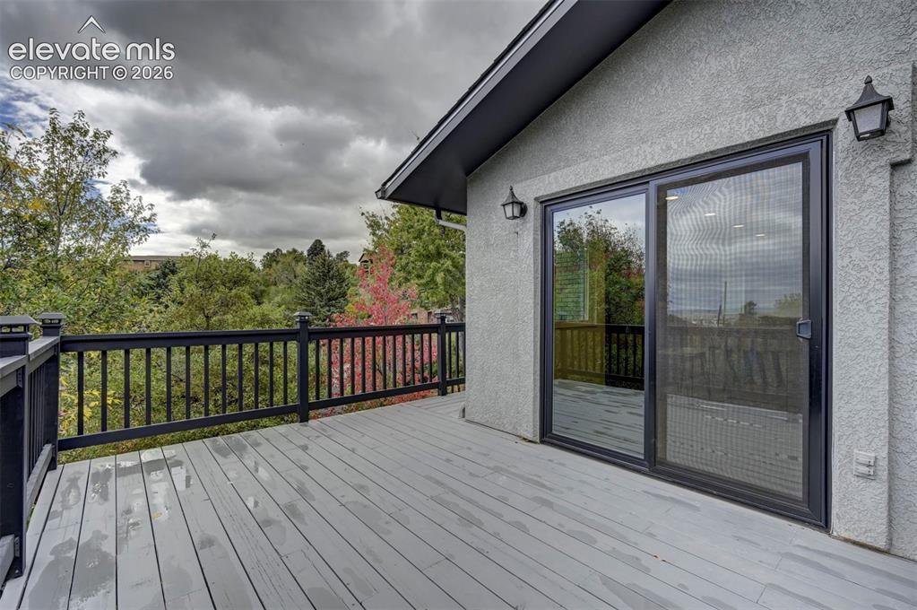 Image 15 of 50: Exterior deck featuring painted wood-finish plank flooring, black metal rai