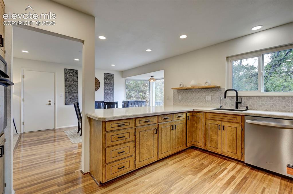 Image 16 of 50: Kitchen featuring light wood-finish cabinetry, stone-style countertops, mat
