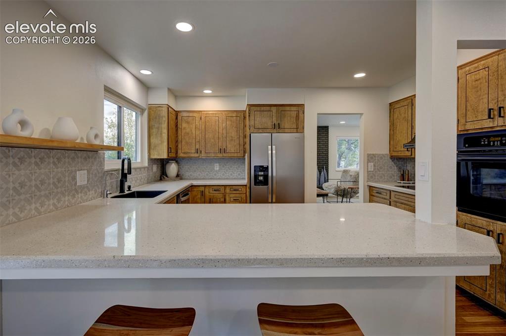 Image 22 of 50: Kitchen featuring a wrap-around stone countertop, wood cabinetry, patterned