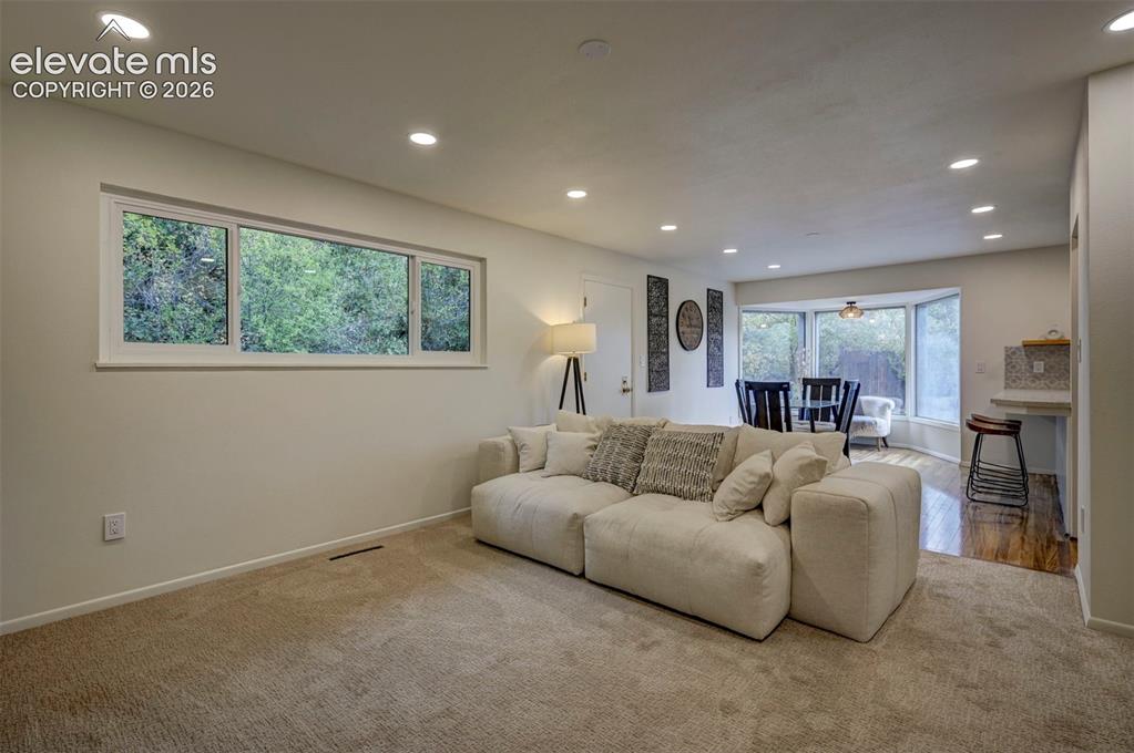 Image 24 of 50: Neutral-toned interior space featuring recessed ceiling lighting, wall-to-w