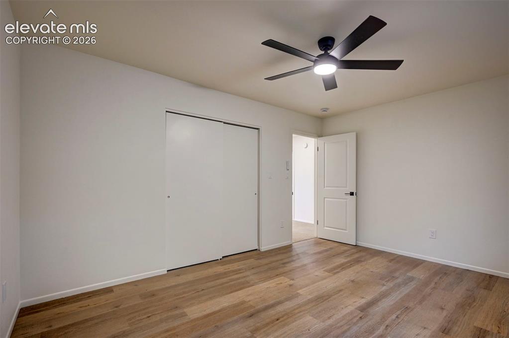 Image 27 of 50: Room featuring wood-finish flooring, a ceiling fan with integrated lighting