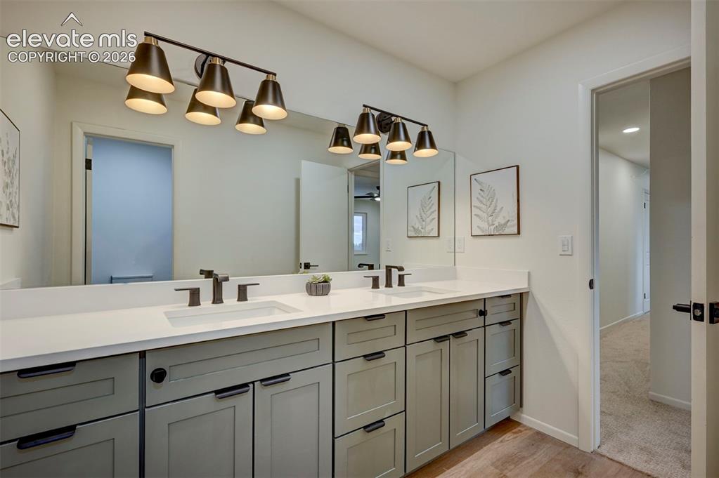 Image 29 of 50: Dual-sink vanity featuring grey cabinetry, solid-surface white countertops,