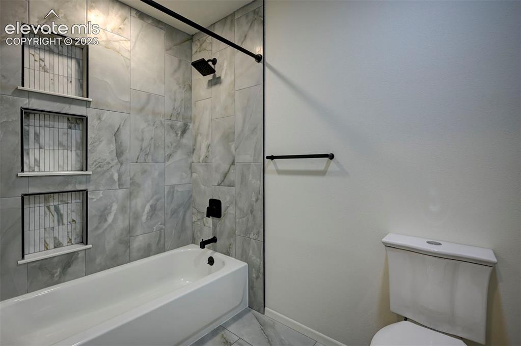 Image 30 of 50: Bathtub featuring large-format stone-look wall tile, triple built-in recess