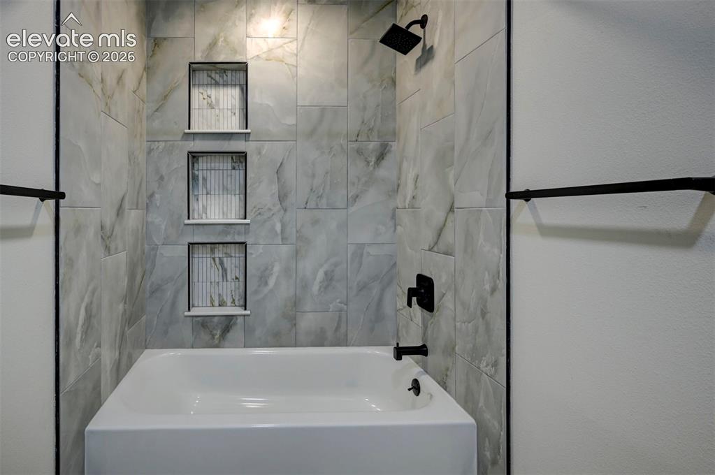 Image 31 of 50: Bathtub with large-format tile surround, three built-in wall niches featuri