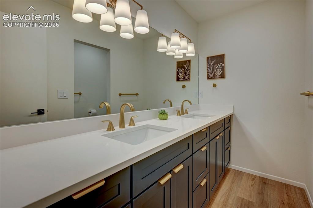Image 34 of 50: Double vanity featuring dark cabinetry, quartz countertops, dual undermount