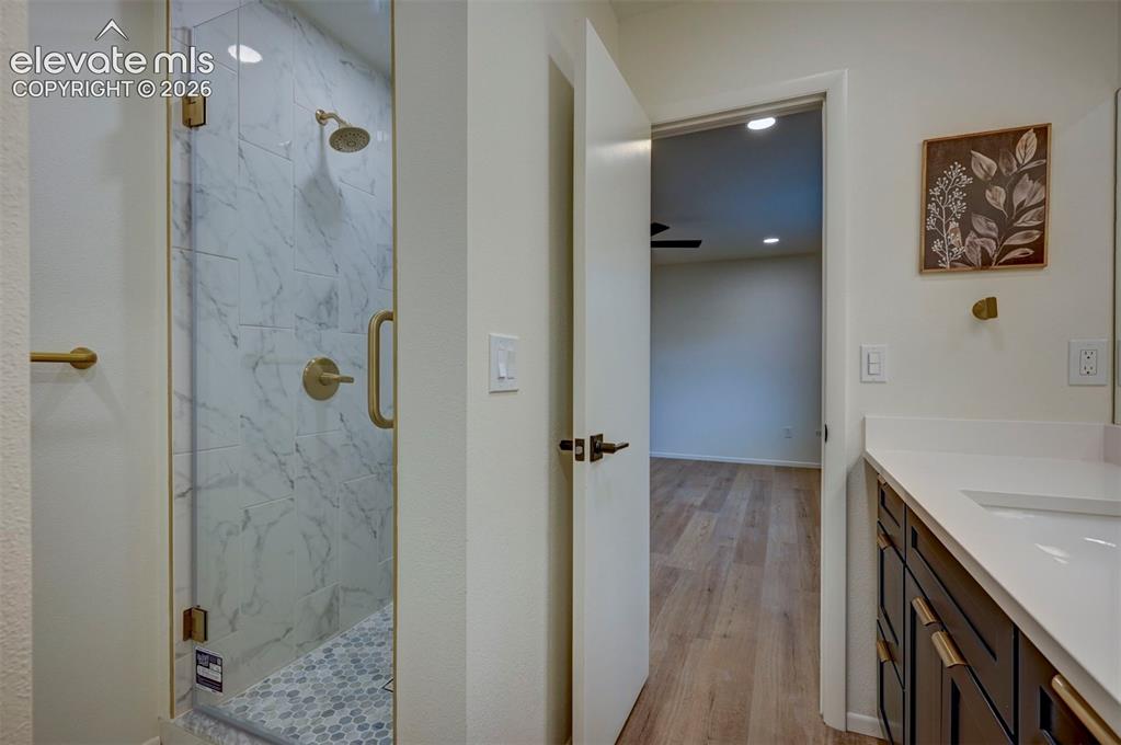Image 35 of 50: Walk-in shower with floor-to-ceiling tile, brass-finish fixtures, and a fra