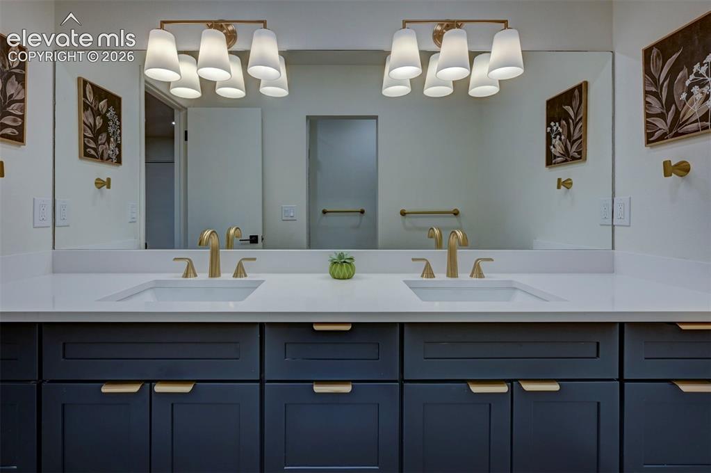 Image 36 of 50: Dual-sink vanity with navy shaker-style cabinetry, white solid-surface coun