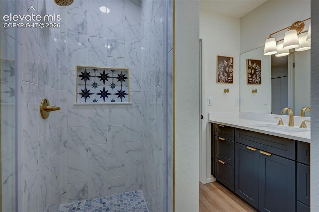 Image 37 of 50: Shower with stone-finish tile surround and decorative inset, brass-tone har