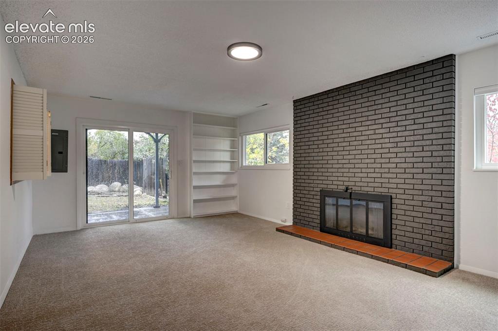 Image 39 of 50: Floor-to-ceiling brick fireplace surround, built-in shelving, sliding glass