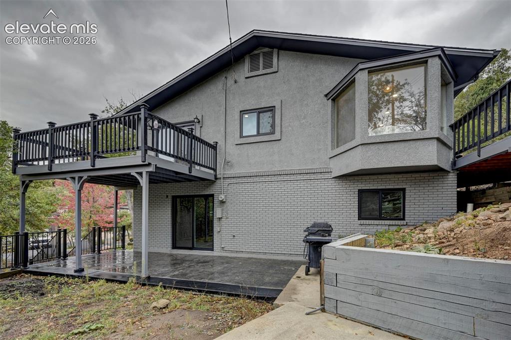 Image 47 of 50: Stucco and painted brick exterior featuring an elevated deck with black rai