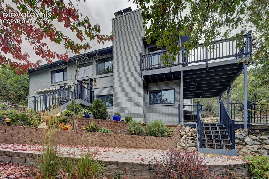 Image 49 of 50: Multi-level home exterior featuring a painted brick facade, a central mason