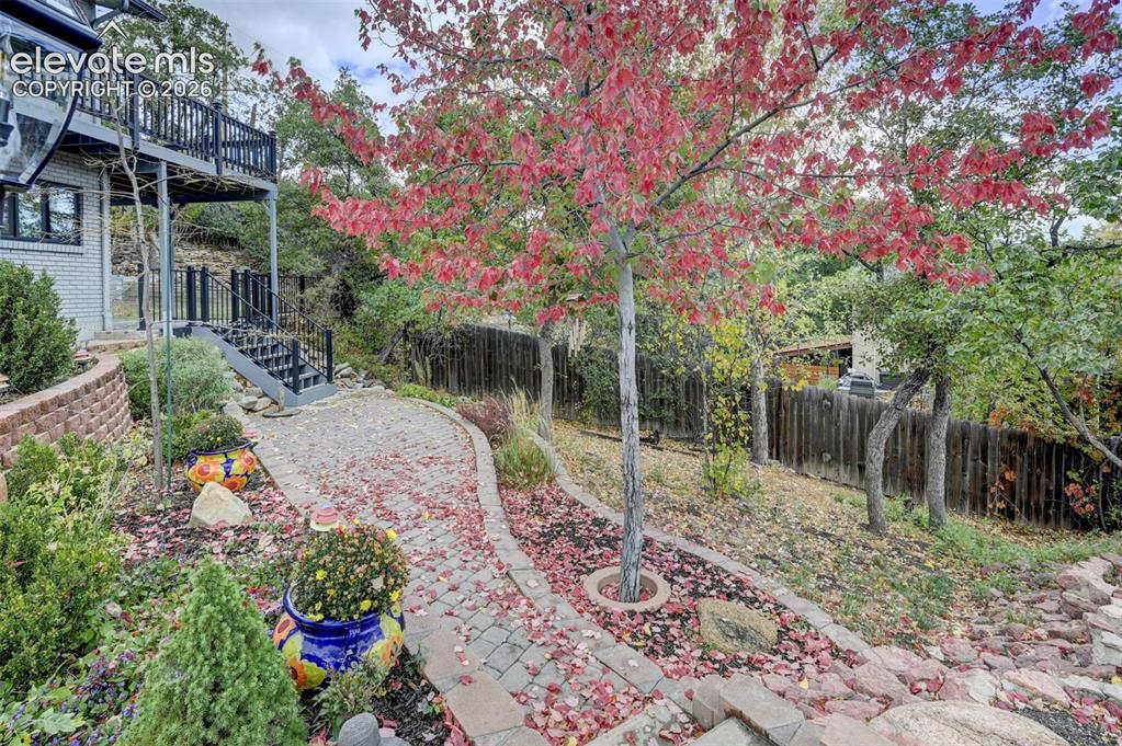 Image 8 of 50: Outdoor space featuring a paver stone walkway, elevated balcony with metal 