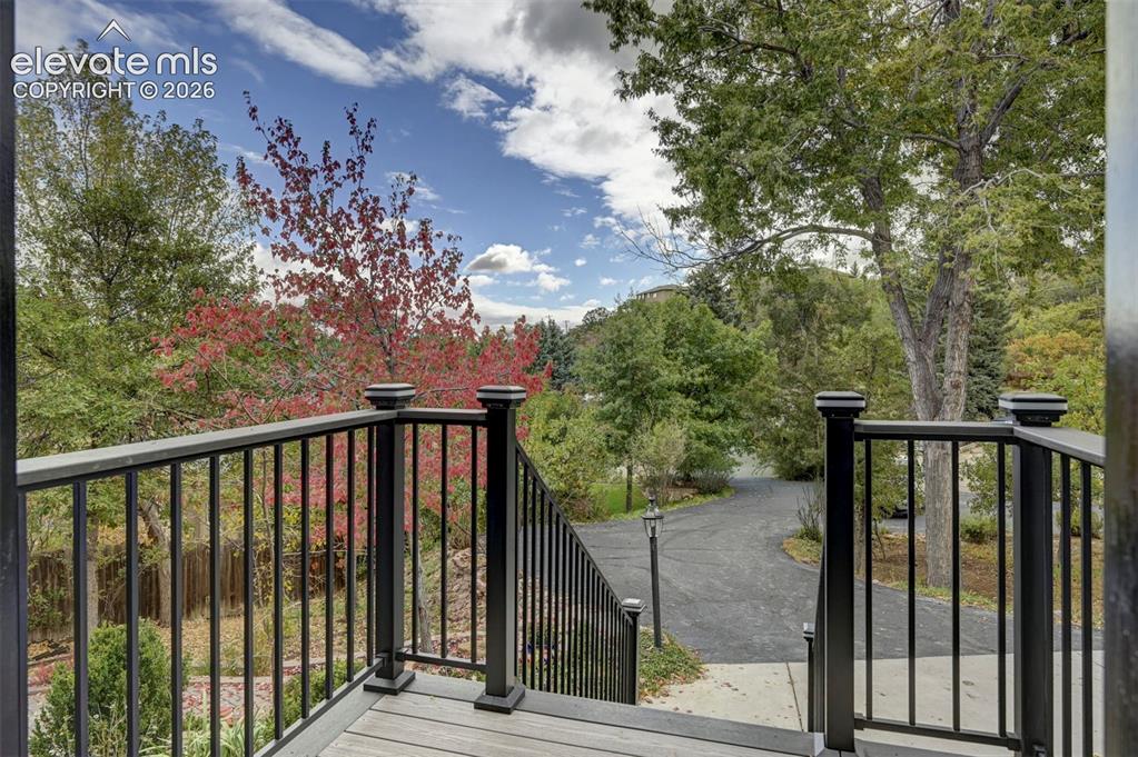 Image 9 of 50: Elevated exterior deck with black metal railing, composite decking, and mat