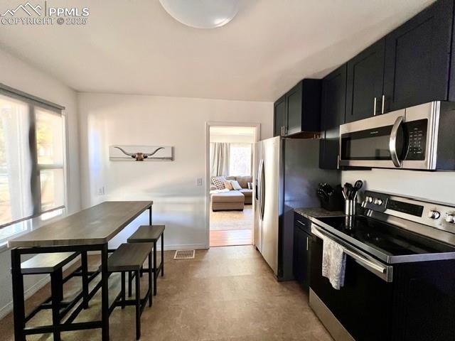 Image 11 of 25: Kitchen featuring dark cabinets, appliances with stainless steel finishes, 