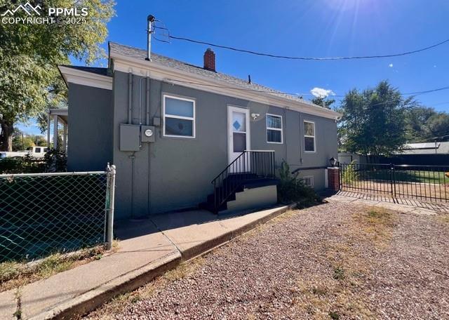 Image 2 of 25: View of side of house featuring a gate and stucco siding