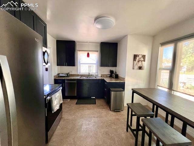 Image 7 of 25: Kitchen with stainless steel appliances, dark cabinets, hanging light fixtu