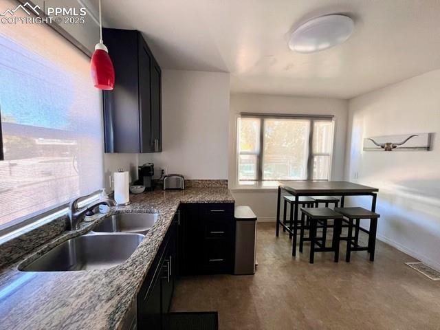 Image 8 of 25: Kitchen featuring stone countertops, pendant lighting, and dark cabinetry