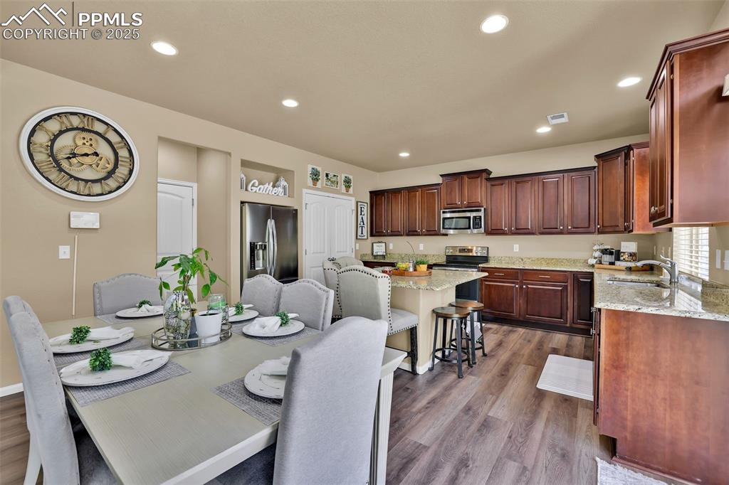 Image 11 of 50: Dining space featuring dark wood-style floors, visible vents, and recessed