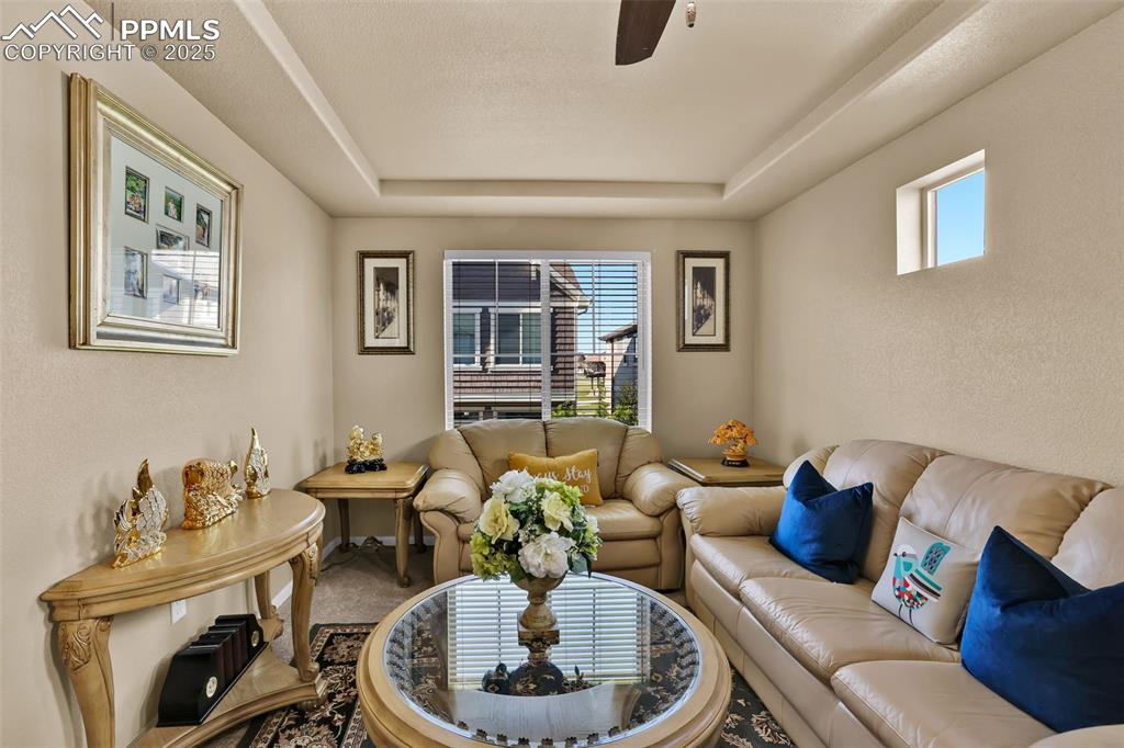 Image 18 of 50: Living area with a ceiling fan, a tray ceiling