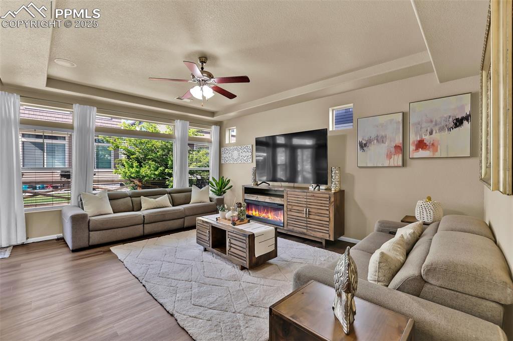 Image 7 of 50: Living area with ceiling fan, a raised ceiling and LVP finished floors