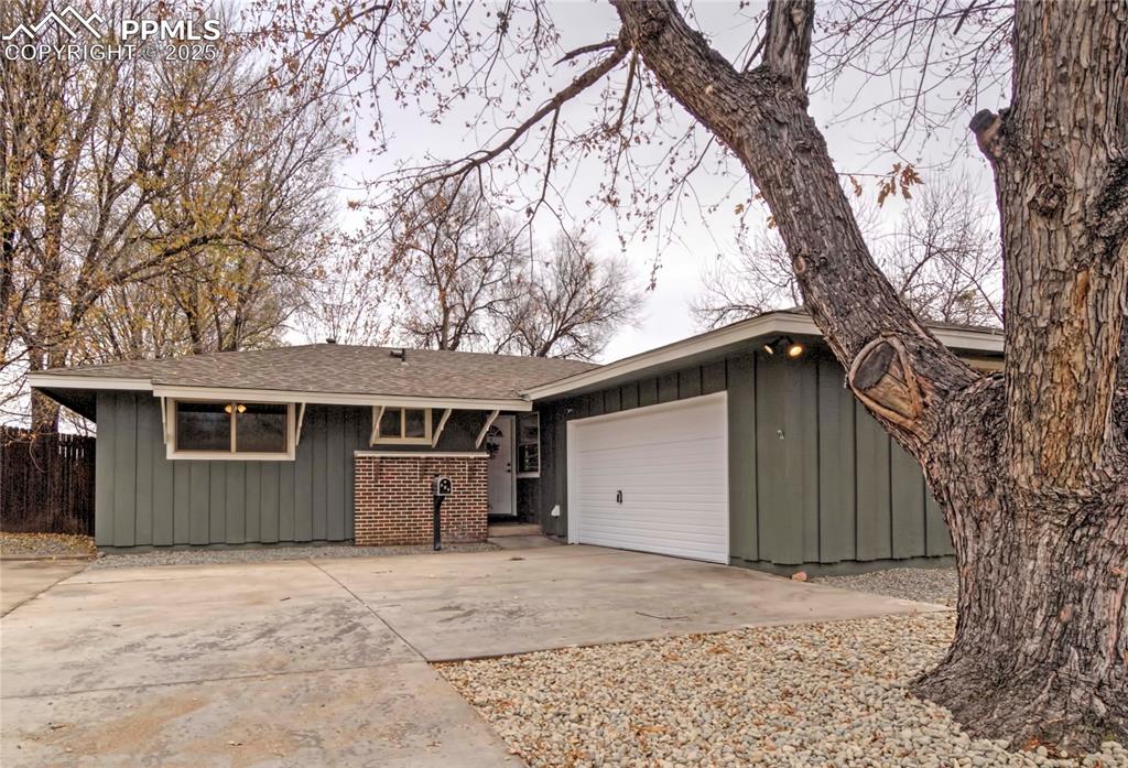 Caption: Single story home featuring board and batten siding, concrete driveway, an attached garage, and a sh