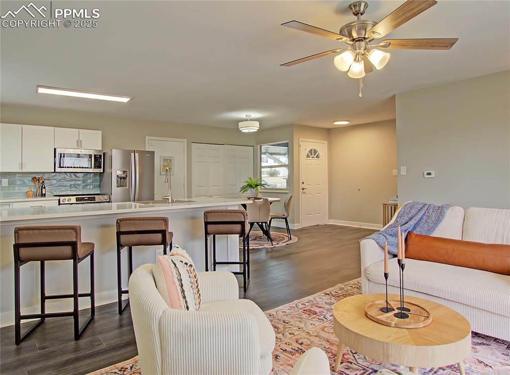 Image 15 of 26: Living area with dark wood-style flooring and ceiling fan