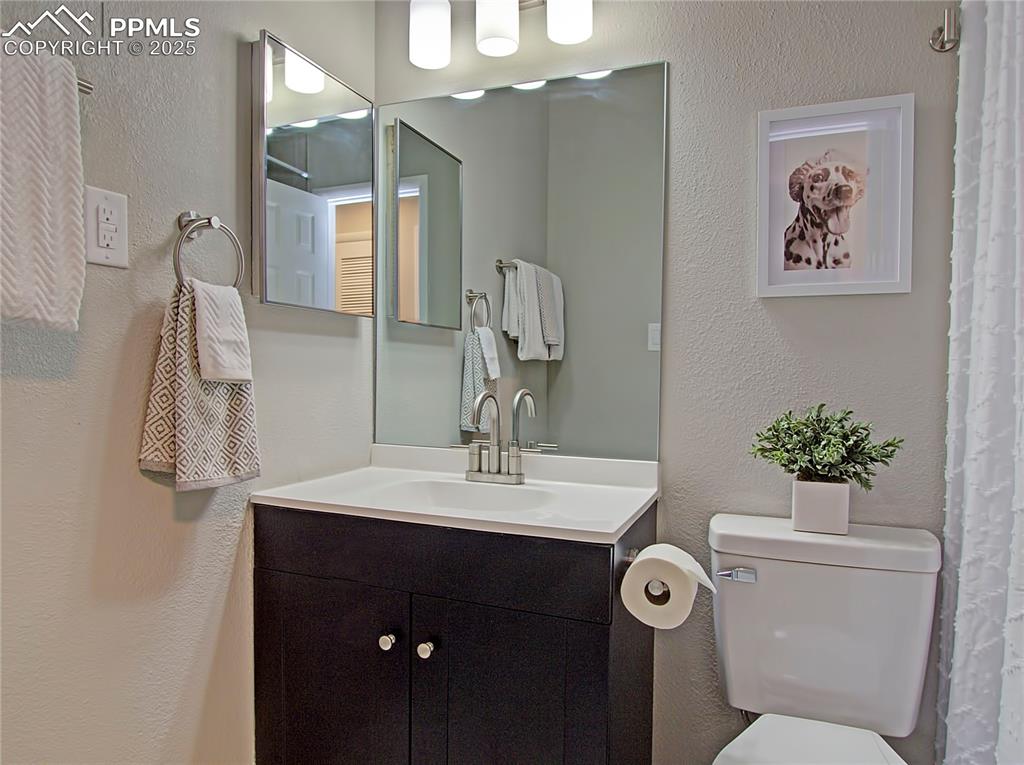 Image 19 of 26: Bathroom with a textured wall, vanity, and a shower with shower curtain