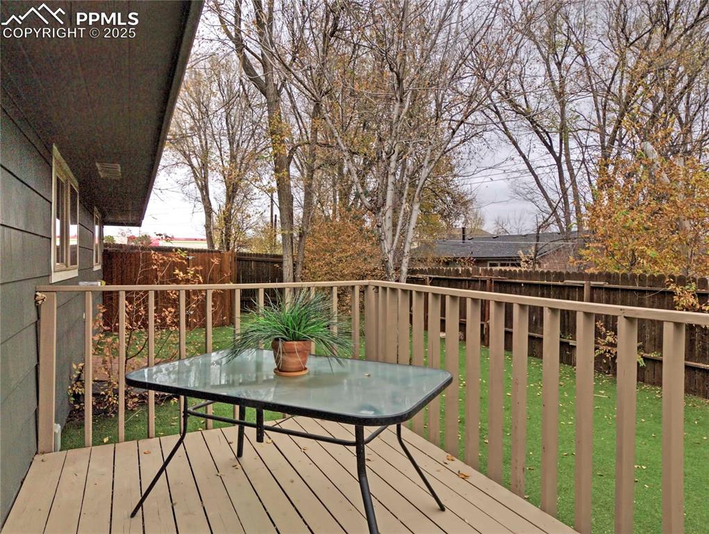 Image 23 of 26: Wooden terrace featuring a fenced backyard and outdoor dining area