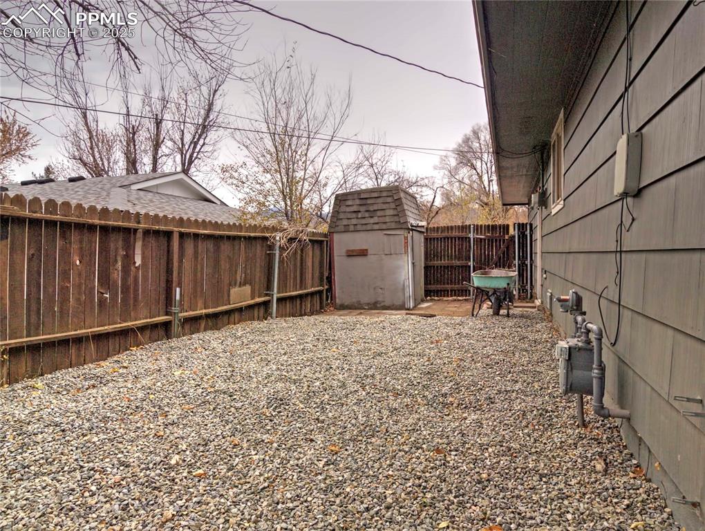Image 26 of 26: Fenced backyard featuring a storage unit and a patio area